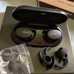 Bose sport earbuds with charger, extra ear holders, manuals.